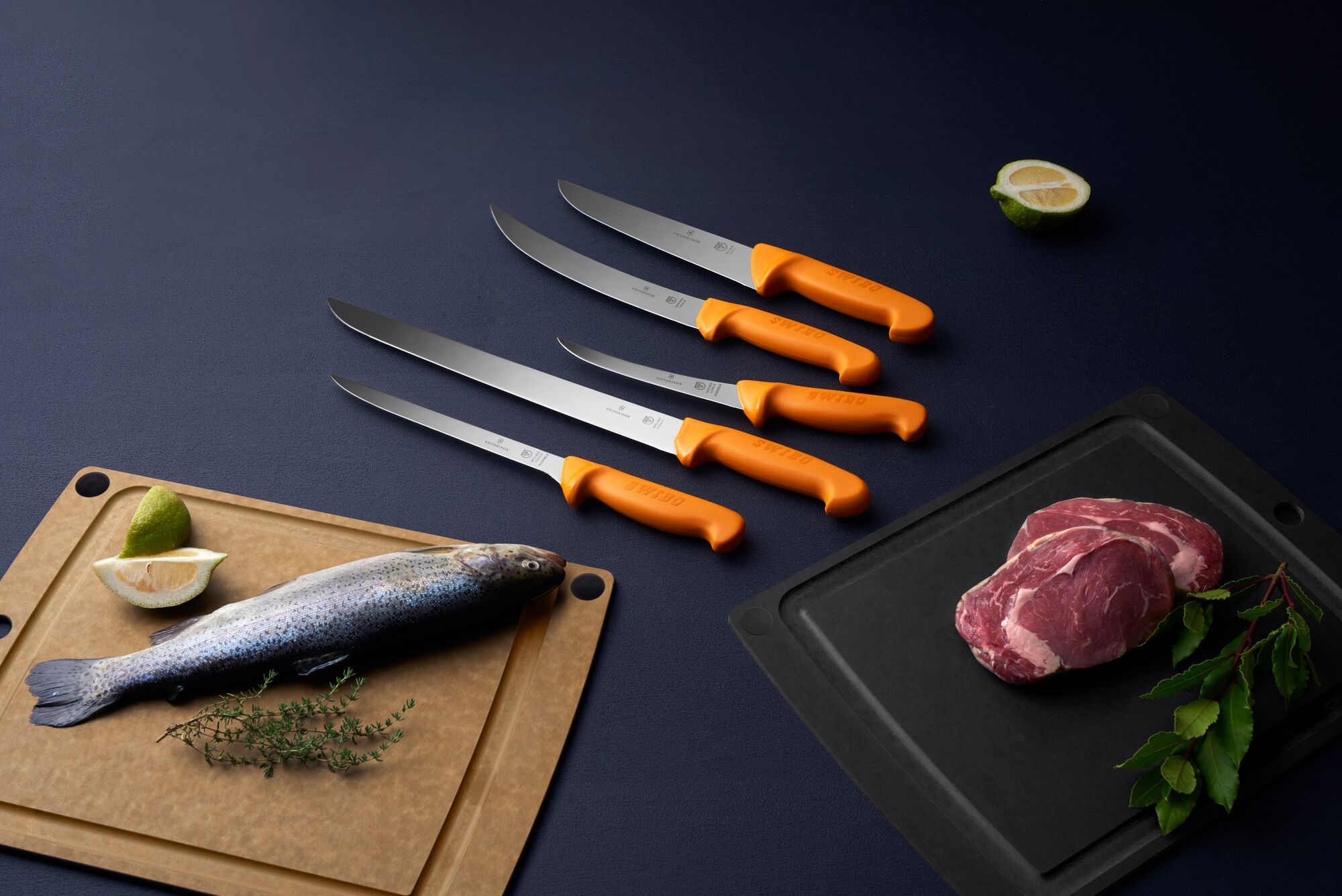 Victorinox Swibo Messer mit orangen Griffen neben Fisch und Fleisch